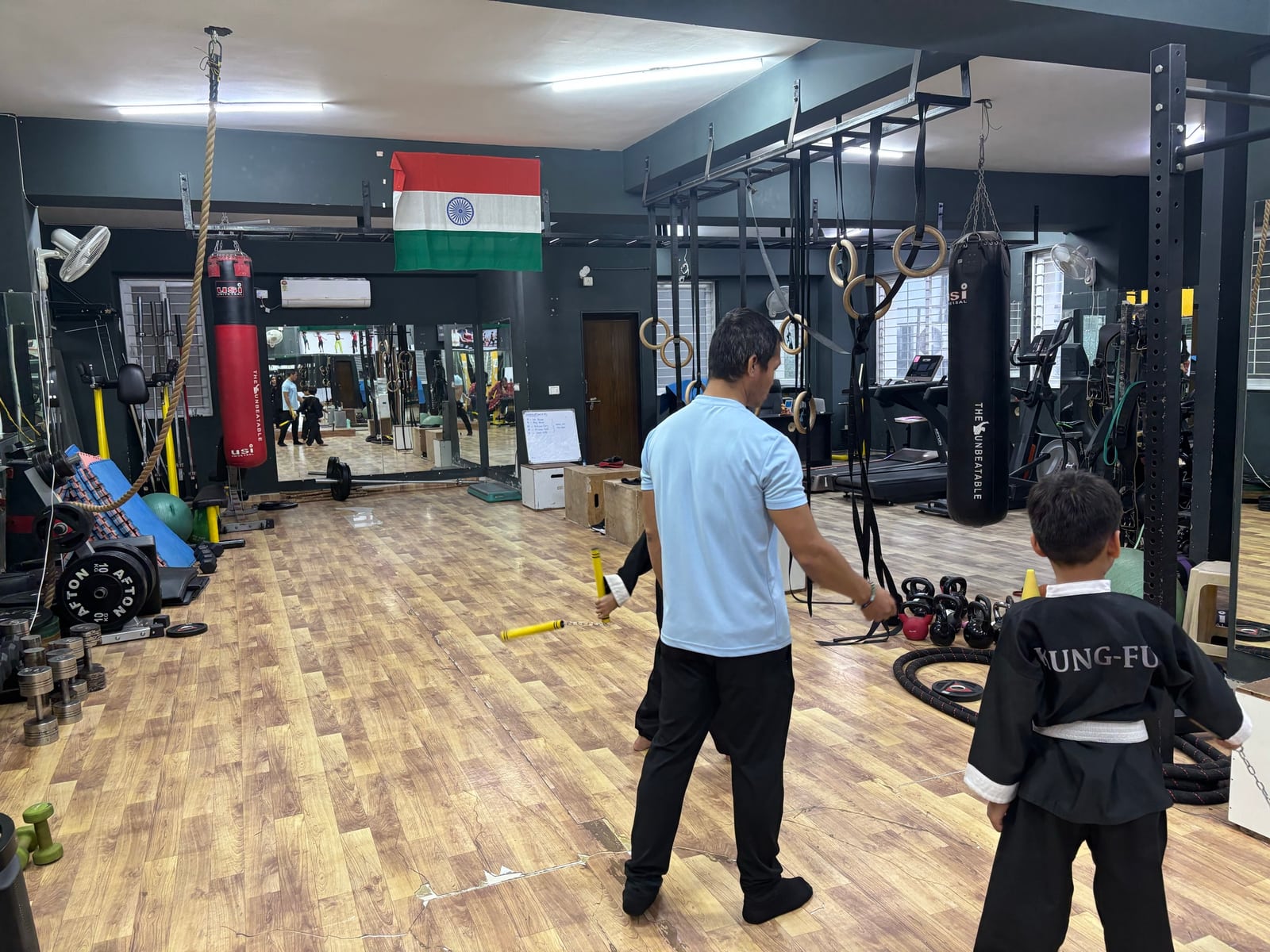 A coach guiding children through martial arts practice at IMFIT